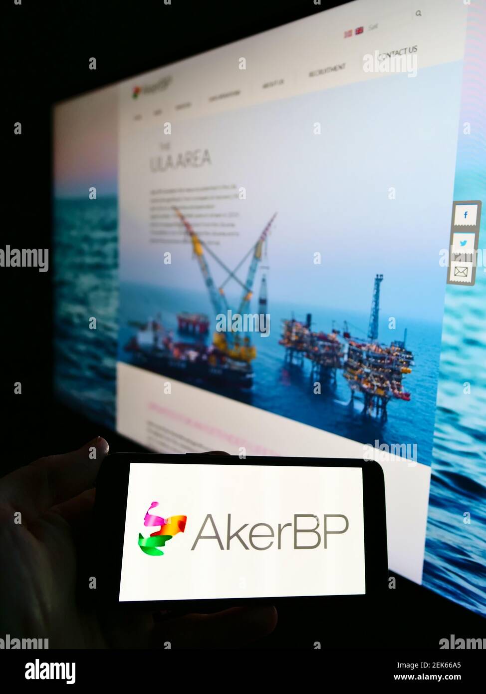 Person holding smartphone with logo of Norwegian oil and gas company Aker BP ASA on screen in front of website. Focus on phone display. Stock Photo