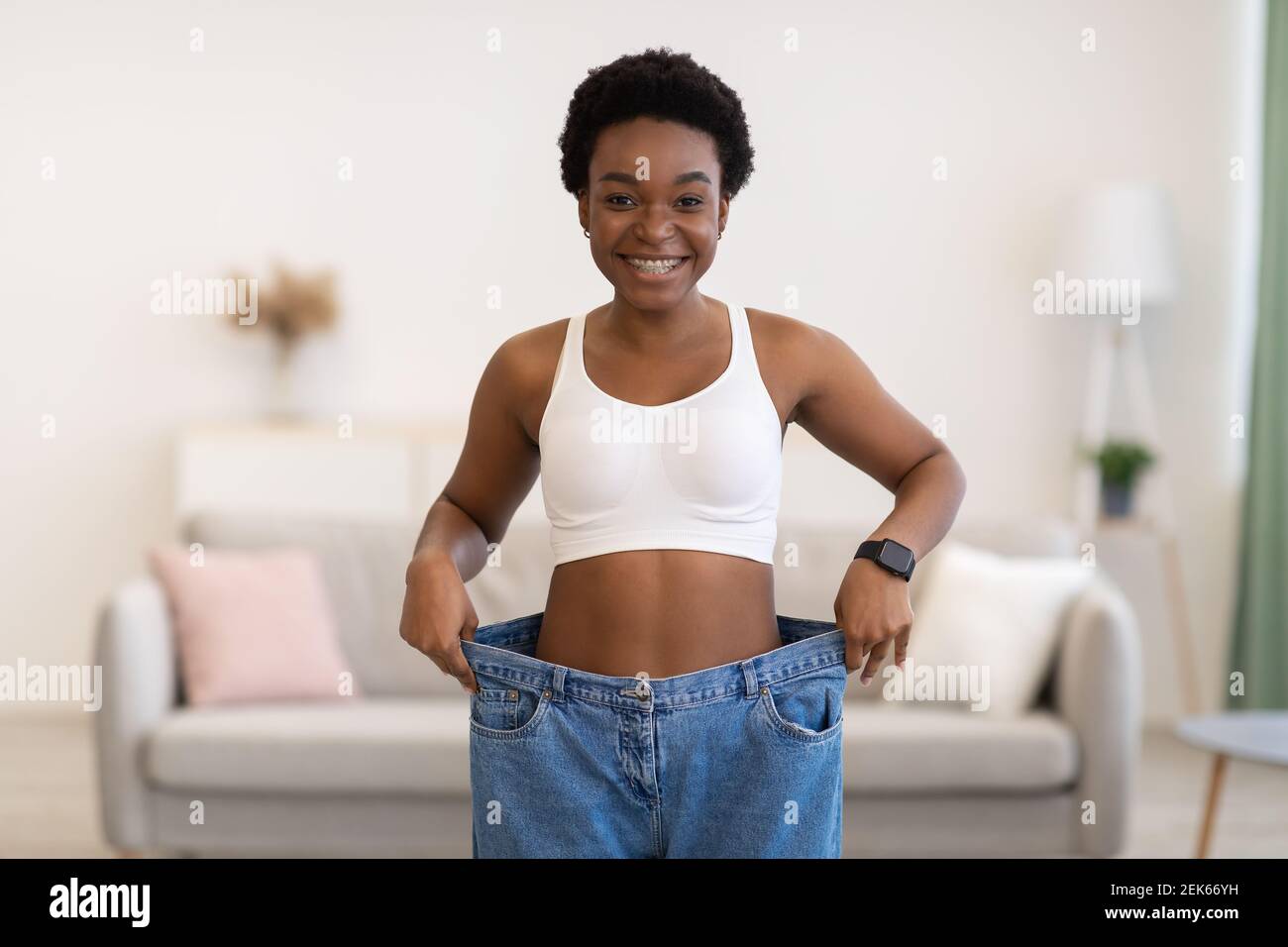 Thin Lady Wearing Large Jeans Showing New Small Size Indoors Stock Photo