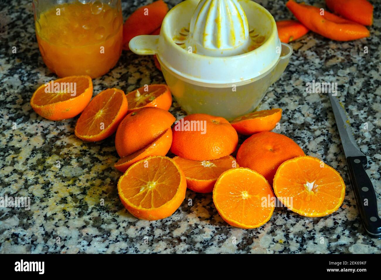 Fresh oranges ready for squeezing to make orange juice on granite kitchen work surface. Stock Photo