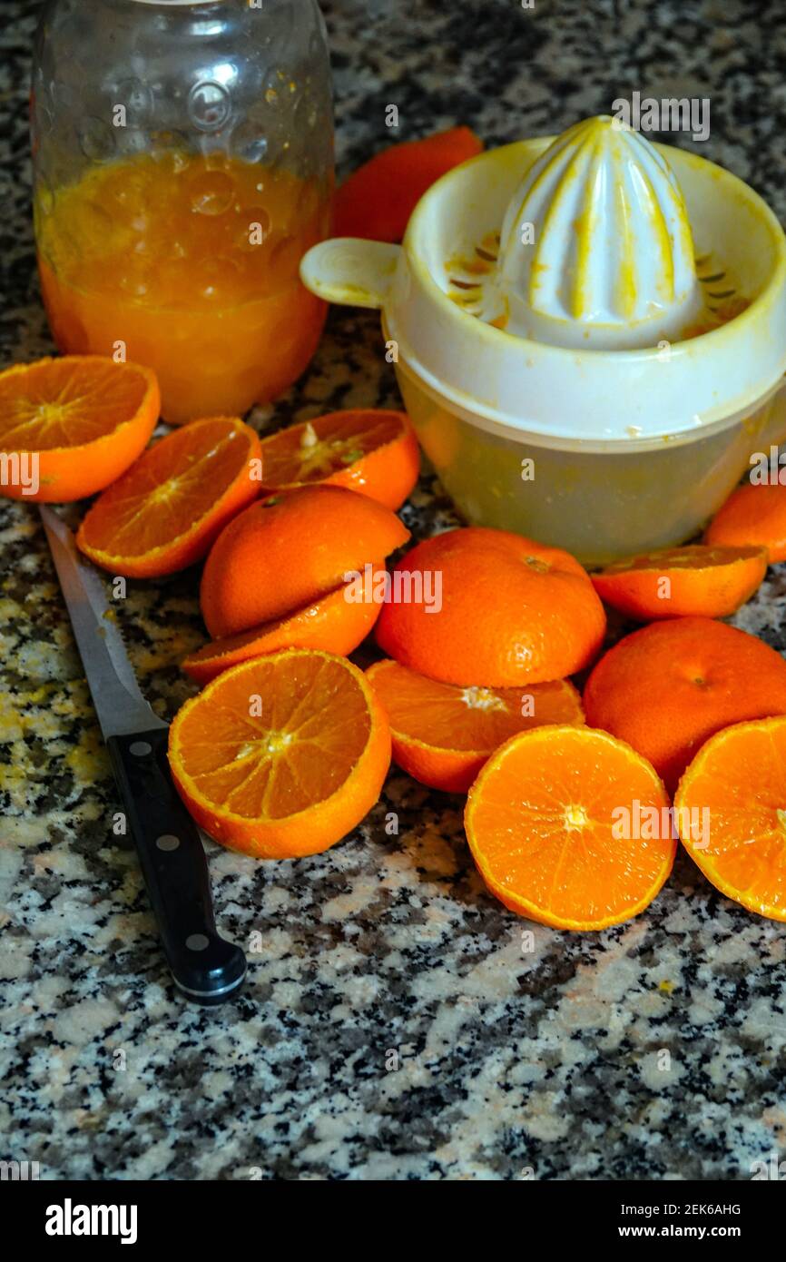 Fresh oranges ready for squeezing to make orange juice on granite kitchen work surface. Stock Photo
