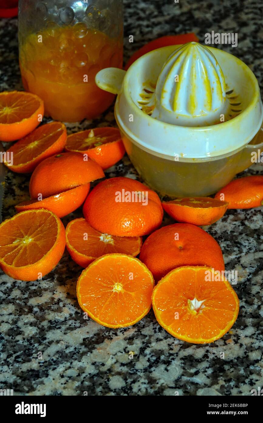 Fresh oranges ready for squeezing to make orange juice on granite kitchen work surface. Stock Photo