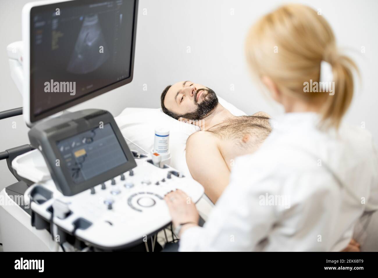 Doctor examining liver of male patient with ultrasound scan in clinic