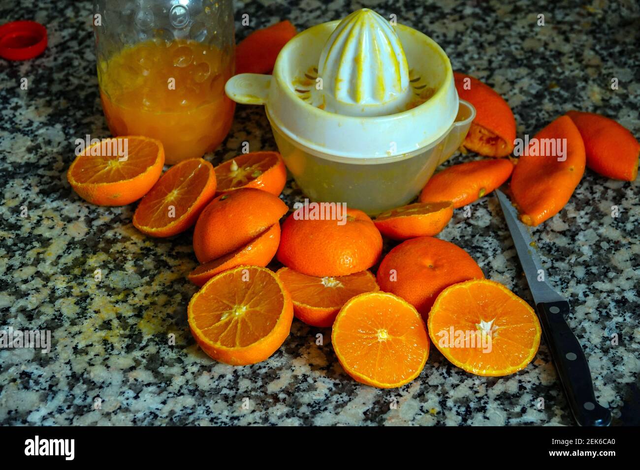 Fresh oranges ready for squeezing to make orange juice on granite kitchen work surface. Stock Photo