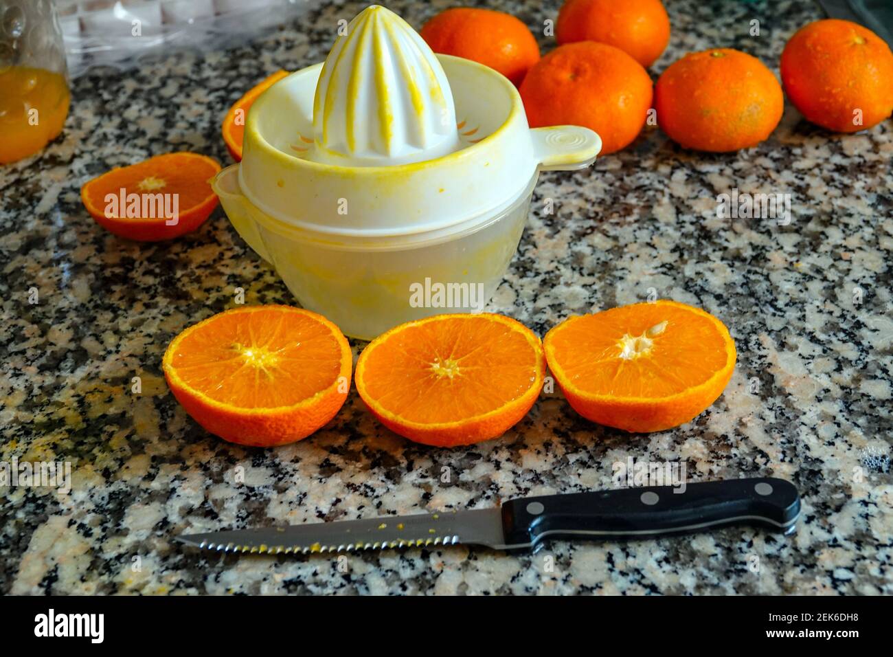 Fresh oranges ready for squeezing to make orange juice on granite kitchen work surface. Stock Photo