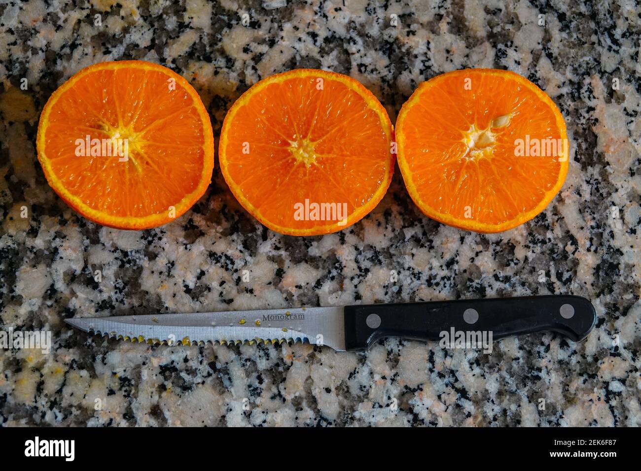 Fresh oranges ready for squeezing to make orange juice on granite kitchen work surface. Stock Photo