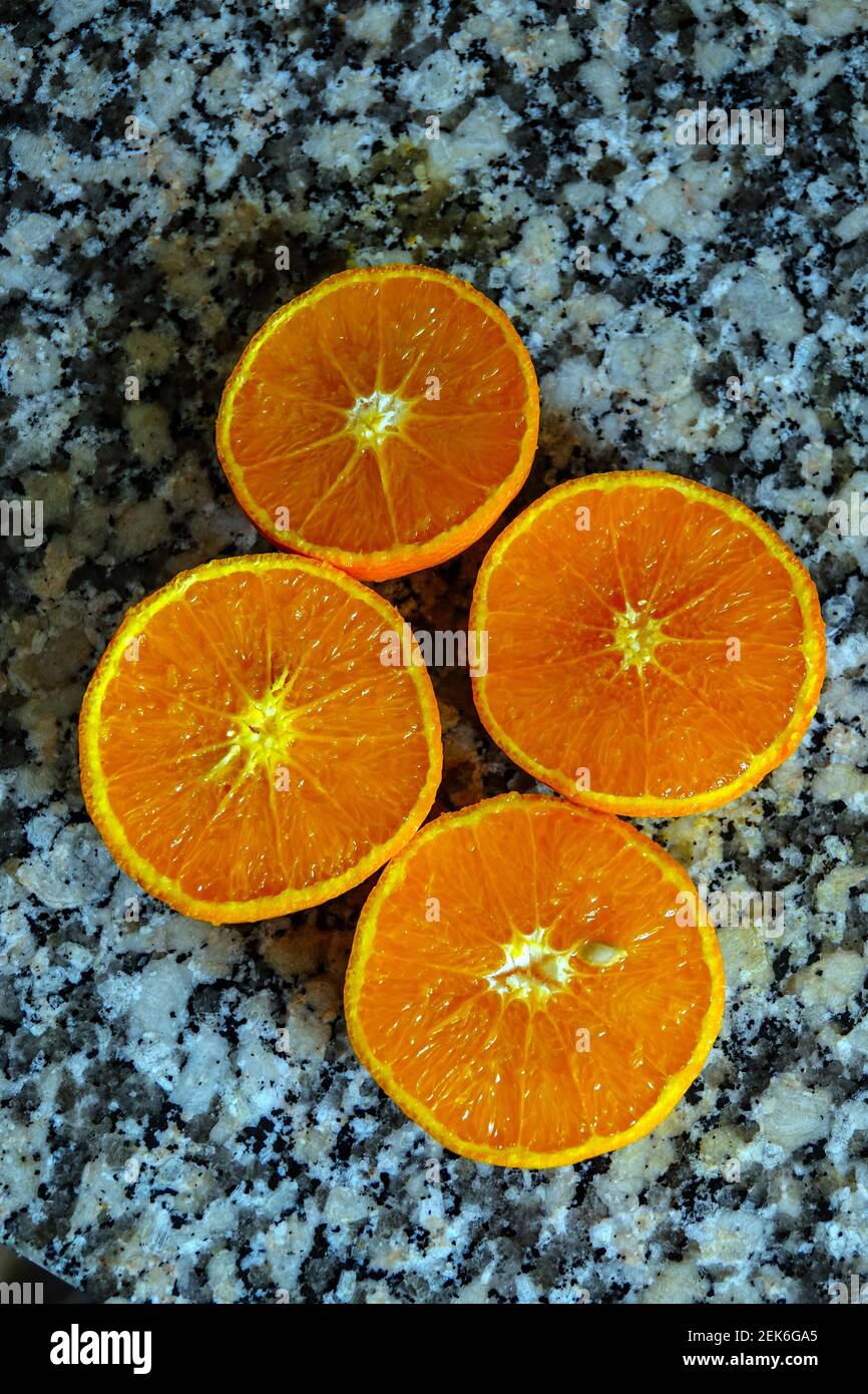 Fresh oranges ready for squeezing to make orange juice on granite kitchen work surface. Stock Photo