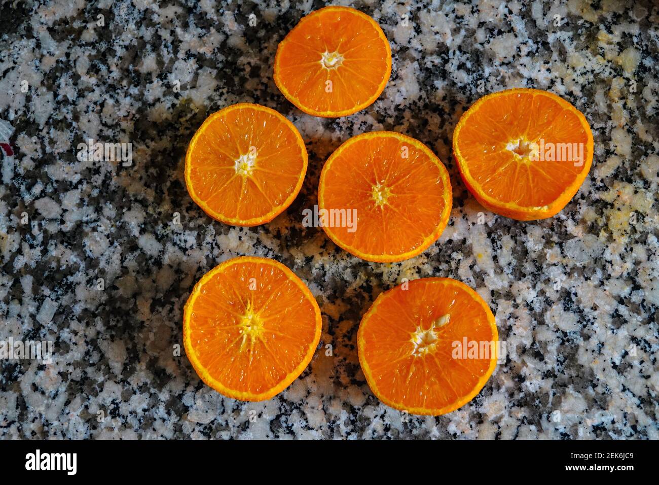 Fresh oranges ready for squeezing to make orange juice on granite kitchen work surface. Stock Photo