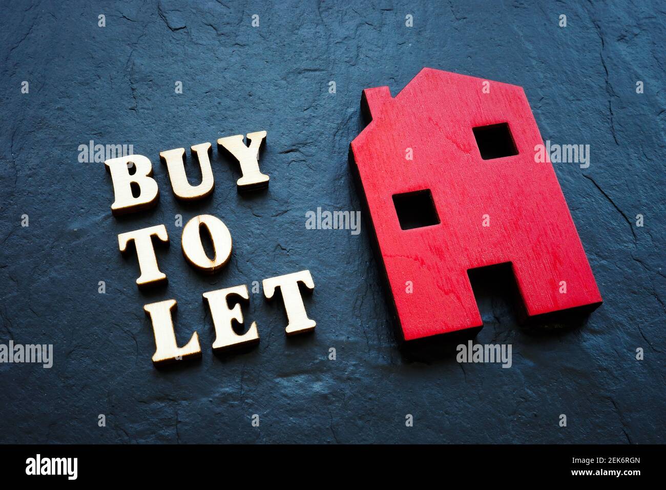Buy to let and red wooden home on the stone. Stock Photo