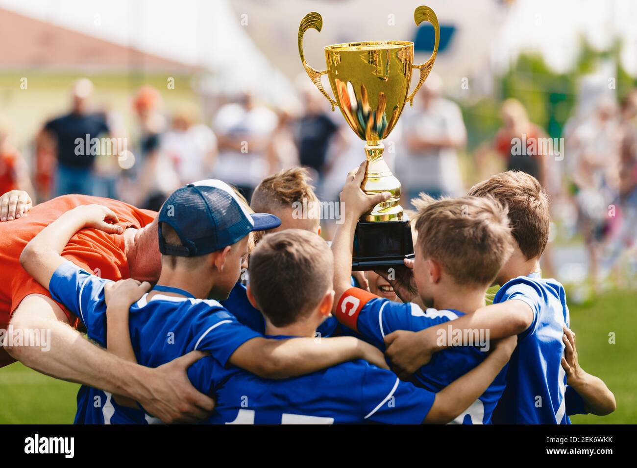 Boys sport team celebrating success with young coach. Team captain