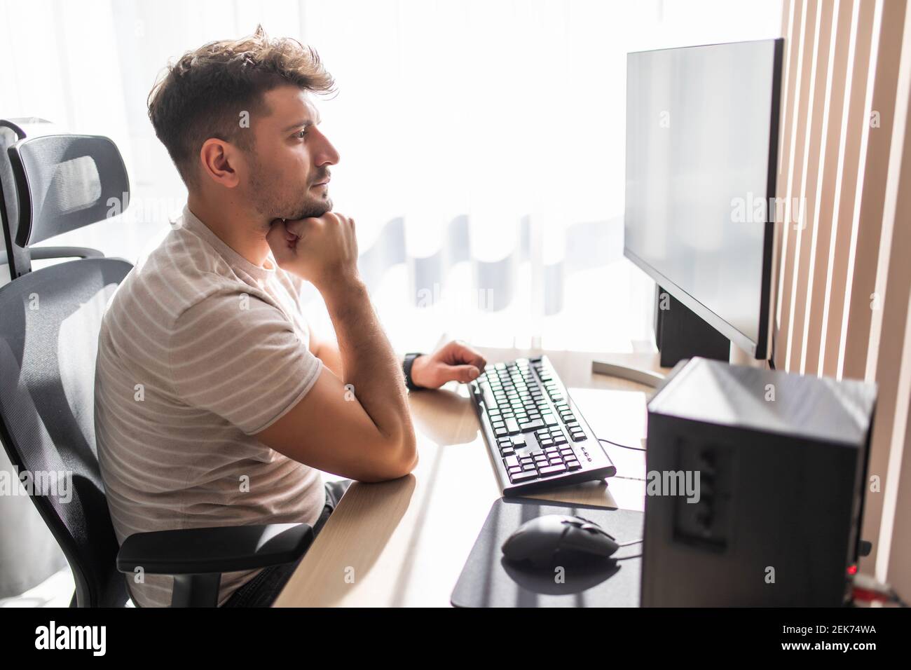 Cheerful man using computer and smiling while sitting on the sofa ...