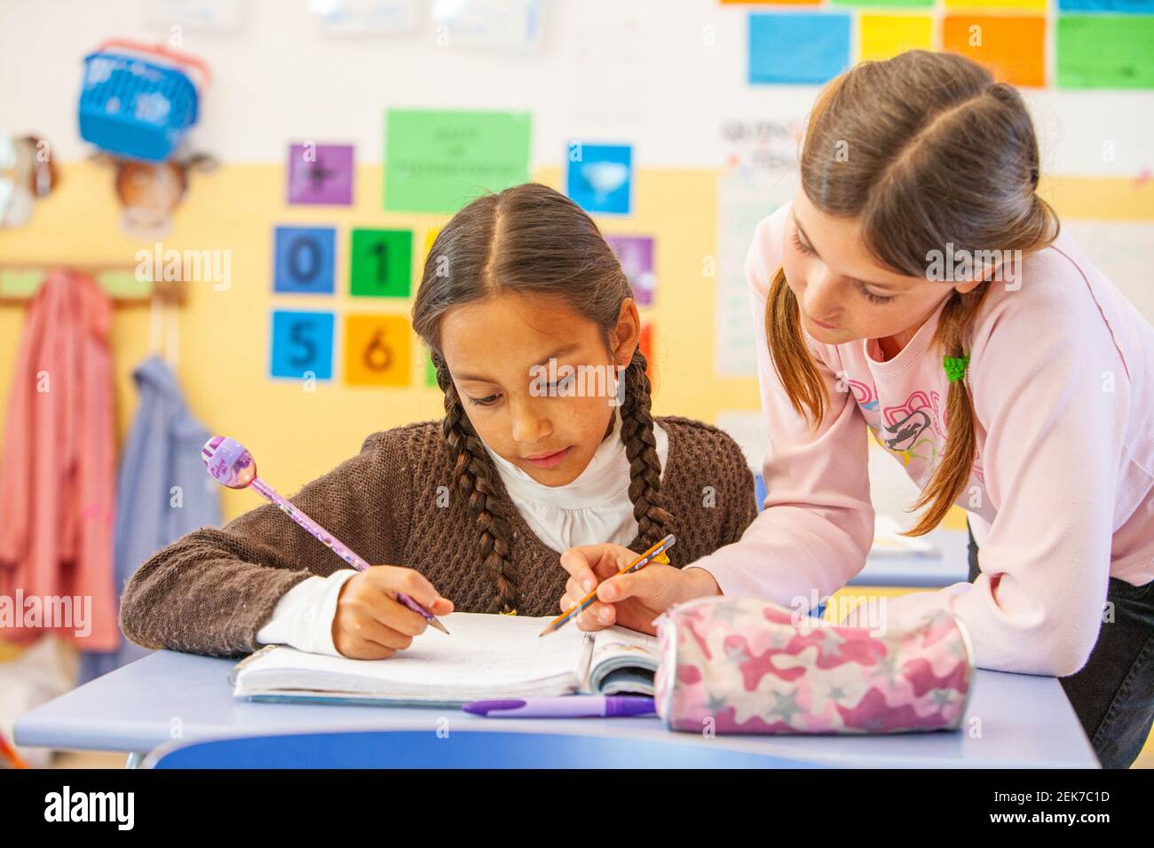 Young girls helping each other in a school classroom Stock Photo