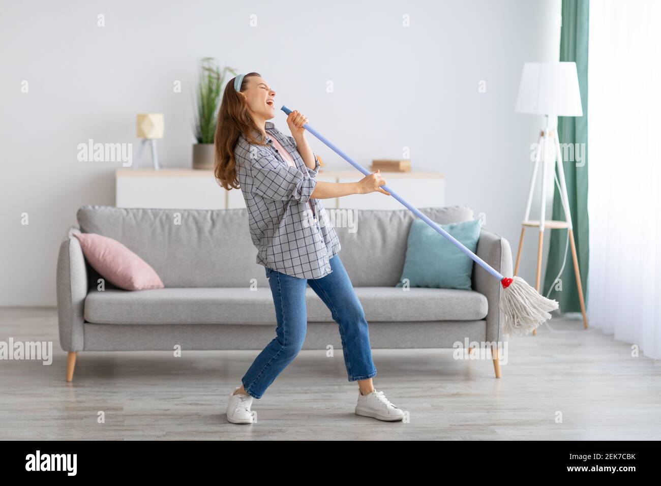 Happy young housewife using mop as microphone, singing during domestic  duties, indoors Stock Photo - Alamy