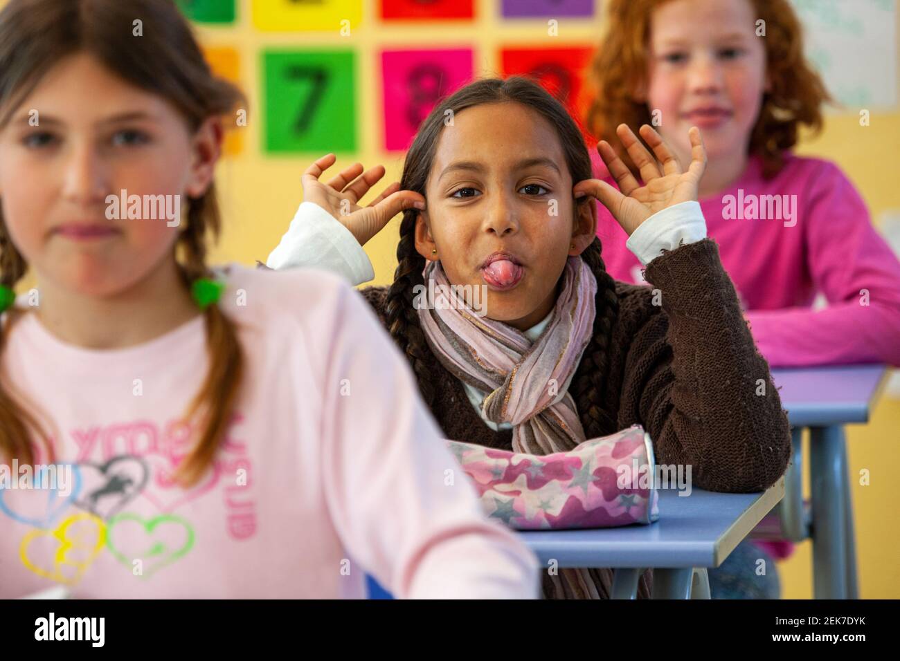 Young girl sticking her tongue out in a school classroom Stock Photo