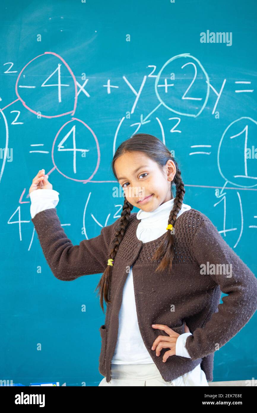 Smart young girl solving equations in an elementary school classroom Stock Photo