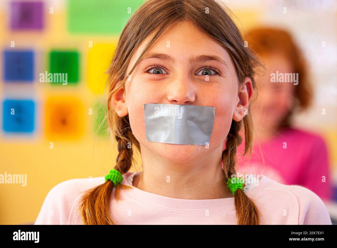 Young child with their mouth taped up in a school classroom Stock Photo