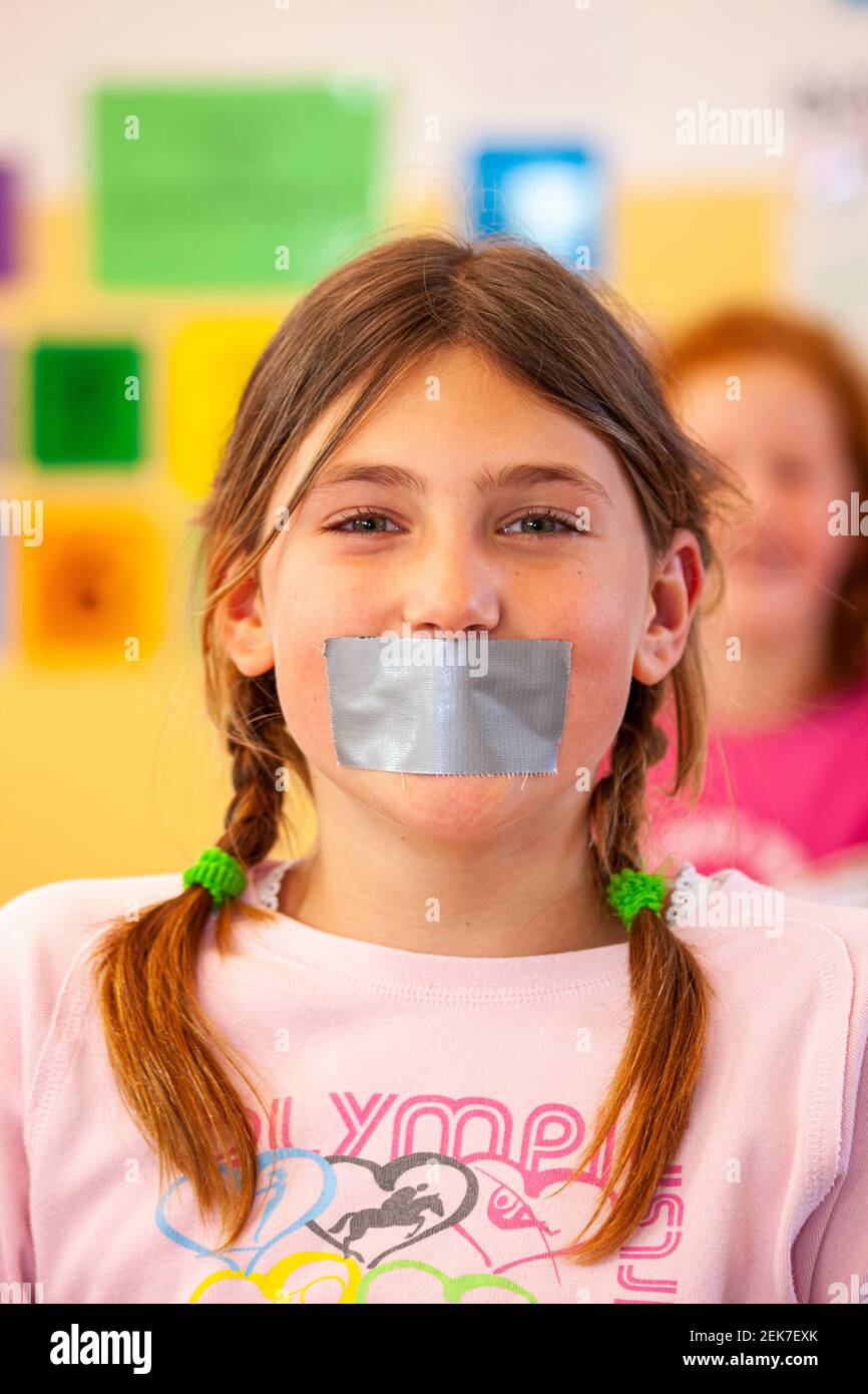 Young child with their mouth taped up in a school classroom Stock Photo