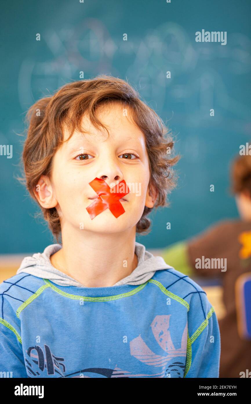 Young child with their mouth taped up in a school classroom Stock Photo