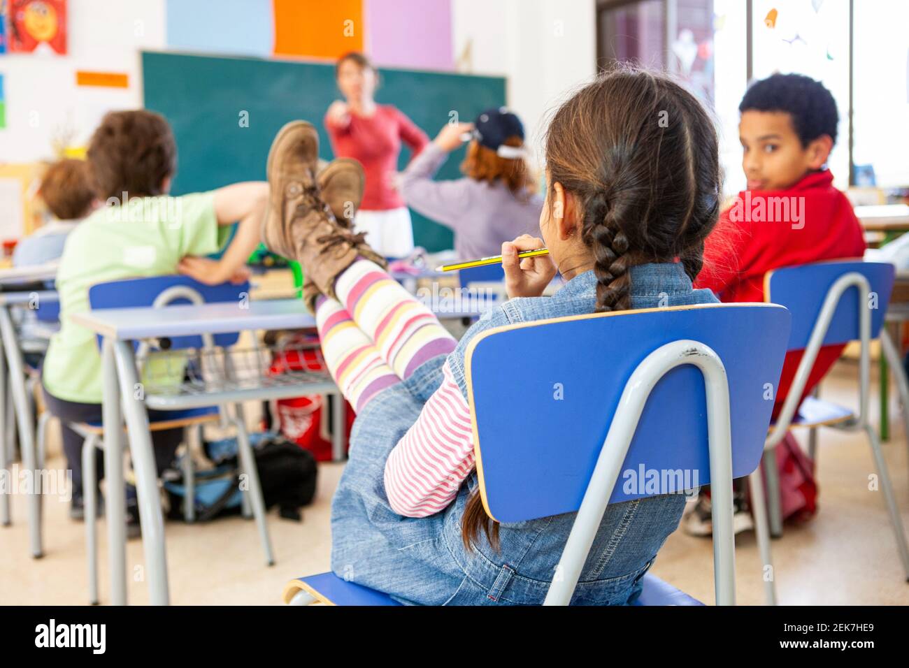 Young girl with a feet up on a desk in a school classroom Stock Photo
