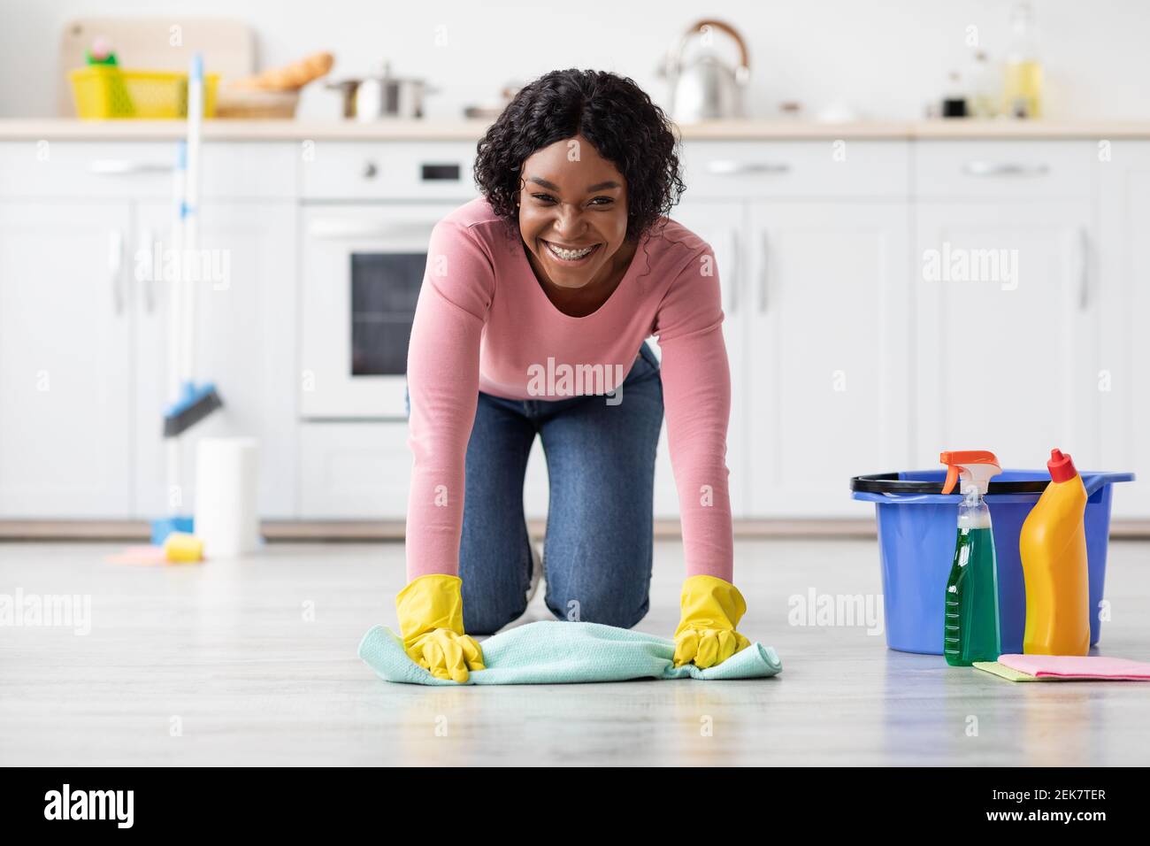 Happy african american woman cleaning floor in kitchen Stock Photo Alamy