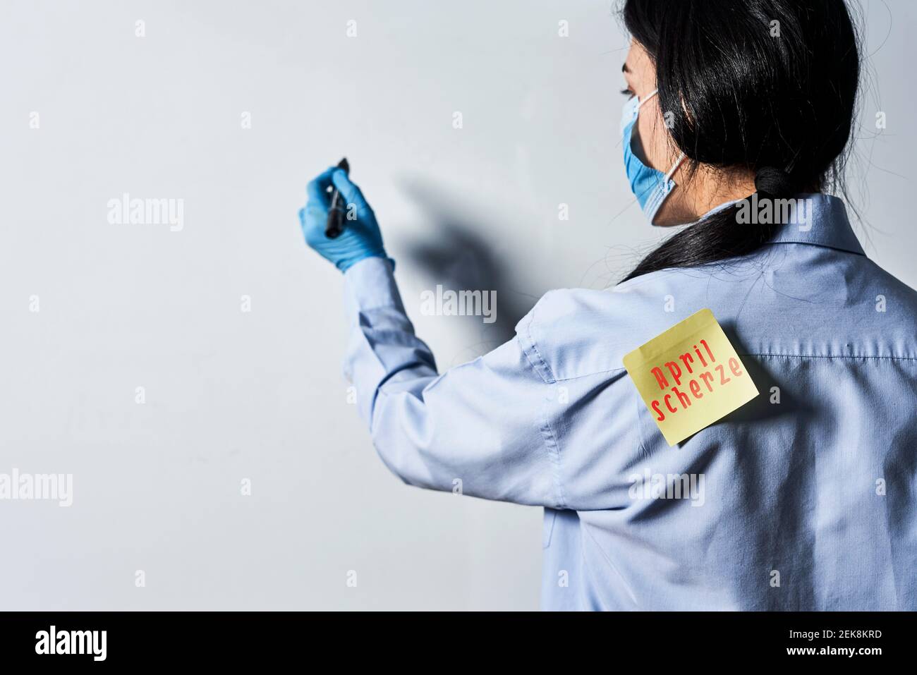 April fools day jokes. A teacher with paper sticker on her back writing