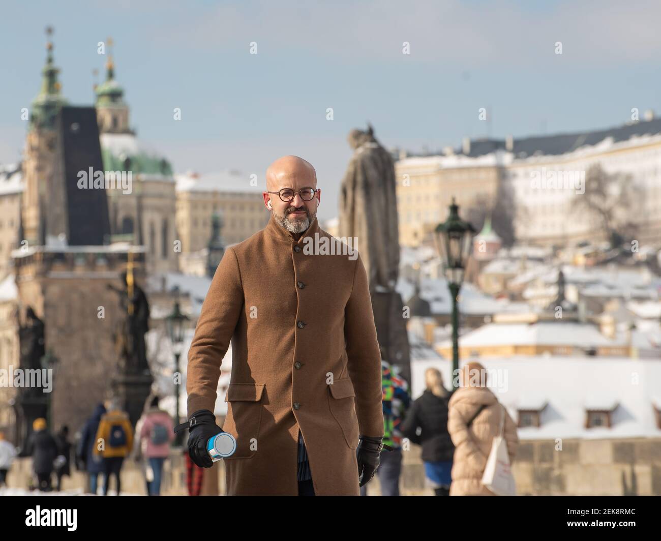 Prague, Czech Republic. 02-23-2021. Tourist and elegant business man in the city center of Prague walking on the Charles Bridge, enjoying a cold day d Stock Photo
