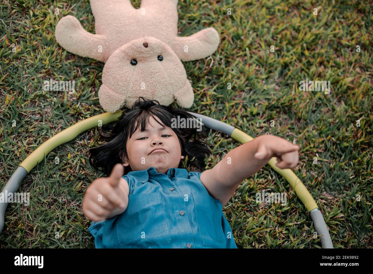 Child with teddy bear lying on the lawn Stock Photo - Alamy