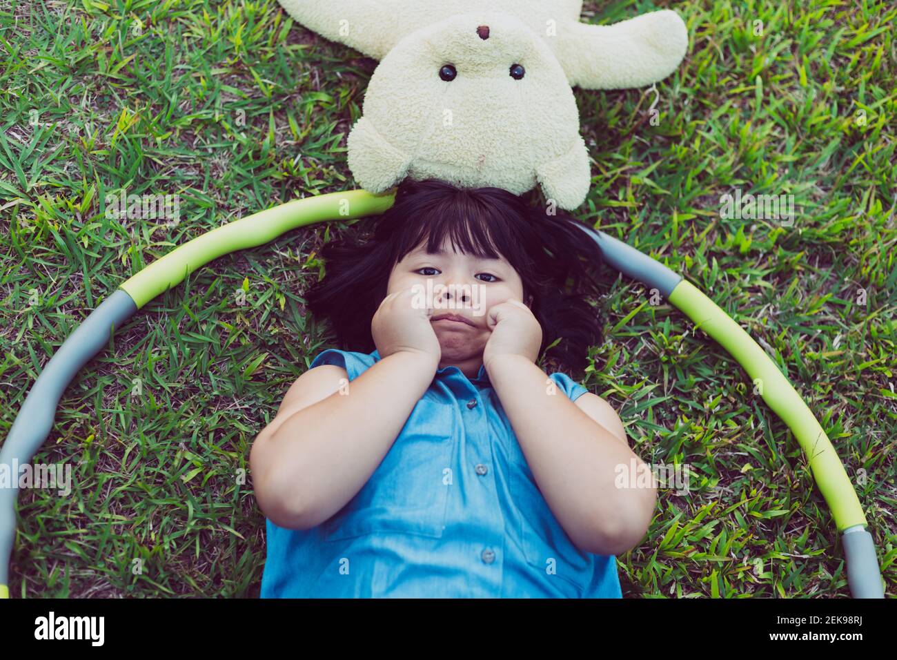 Child with teddy bear lying on the lawn Stock Photo - Alamy
