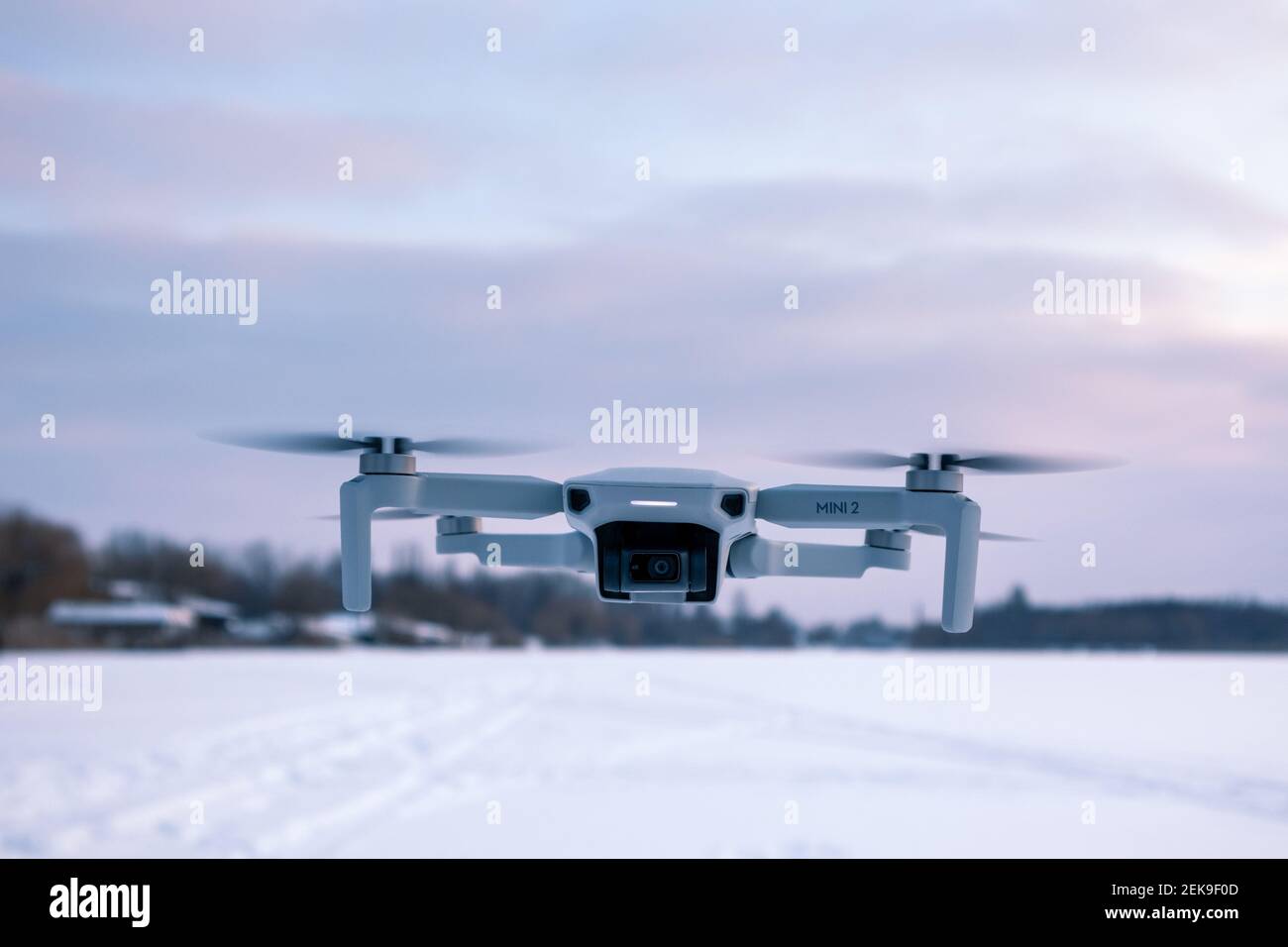 Kharkiv, Ukraine - February 21, 2021: Dji Mavic Mini 2 drone flying in winter snowy landscape in sunset purple clouds. New quadcopter device hovering Stock Photo