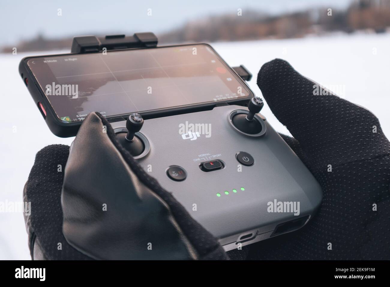 Kharkiv, Ukraine - February 21, 2021: Dji Mavic Mini 2 (dji air 2) drone remote control in hands in winter gloves with connected phone. Operating dron Stock Photo