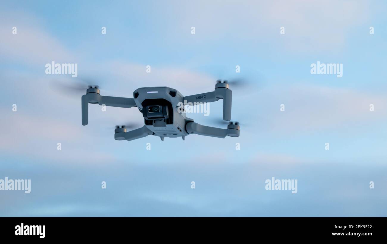 Kharkiv, Ukraine - February 21, 2021: Dji Mavic Mini 2 drone flying in blue sky with sunset purple clouds. New quadcopter device hovering on winter co Stock Photo