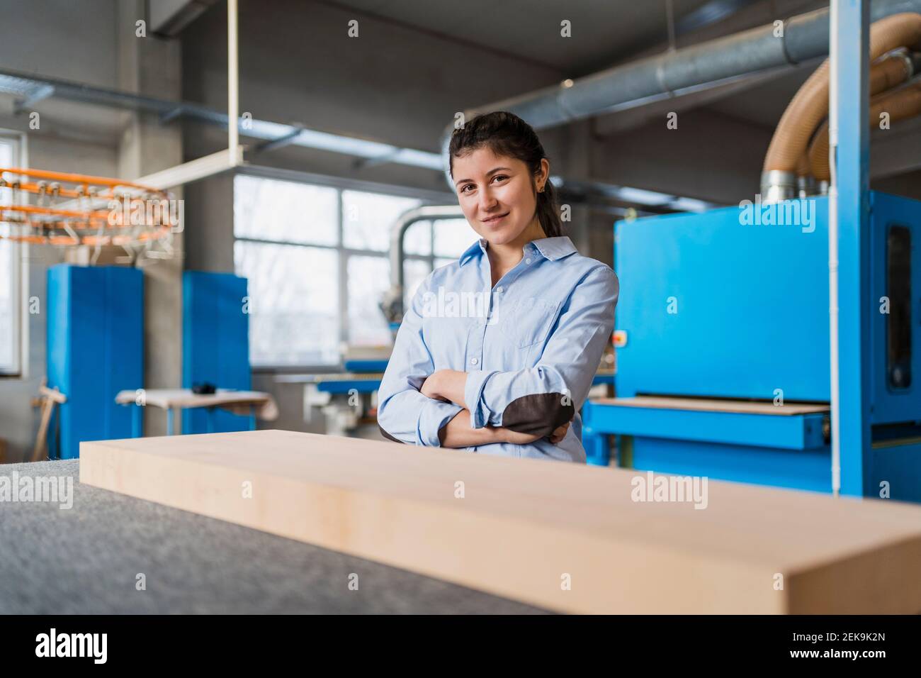 Smiling businesswoman with arms crossed standing at industry Stock Photo
