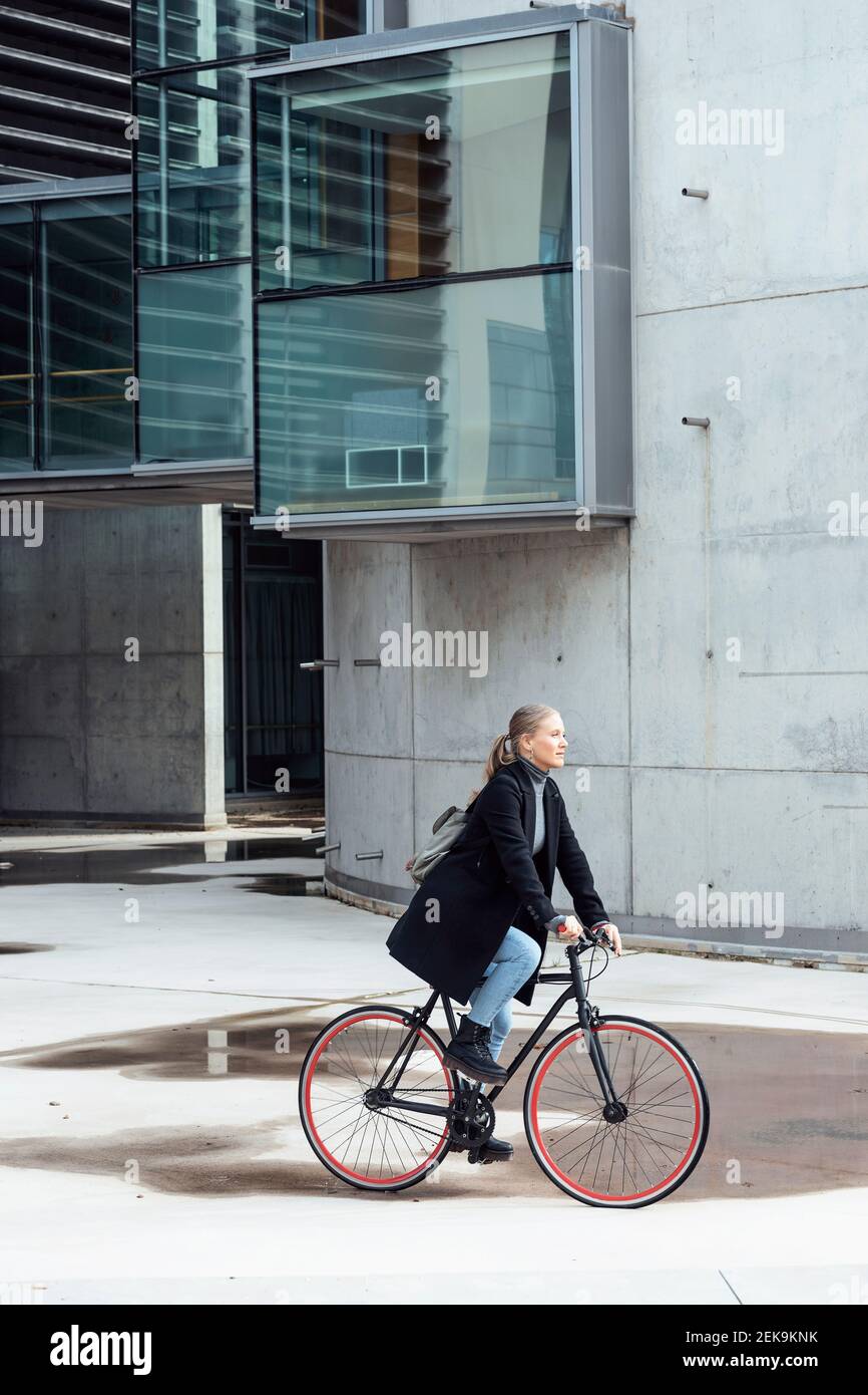 Woman doing cycling on road by building Stock Photo