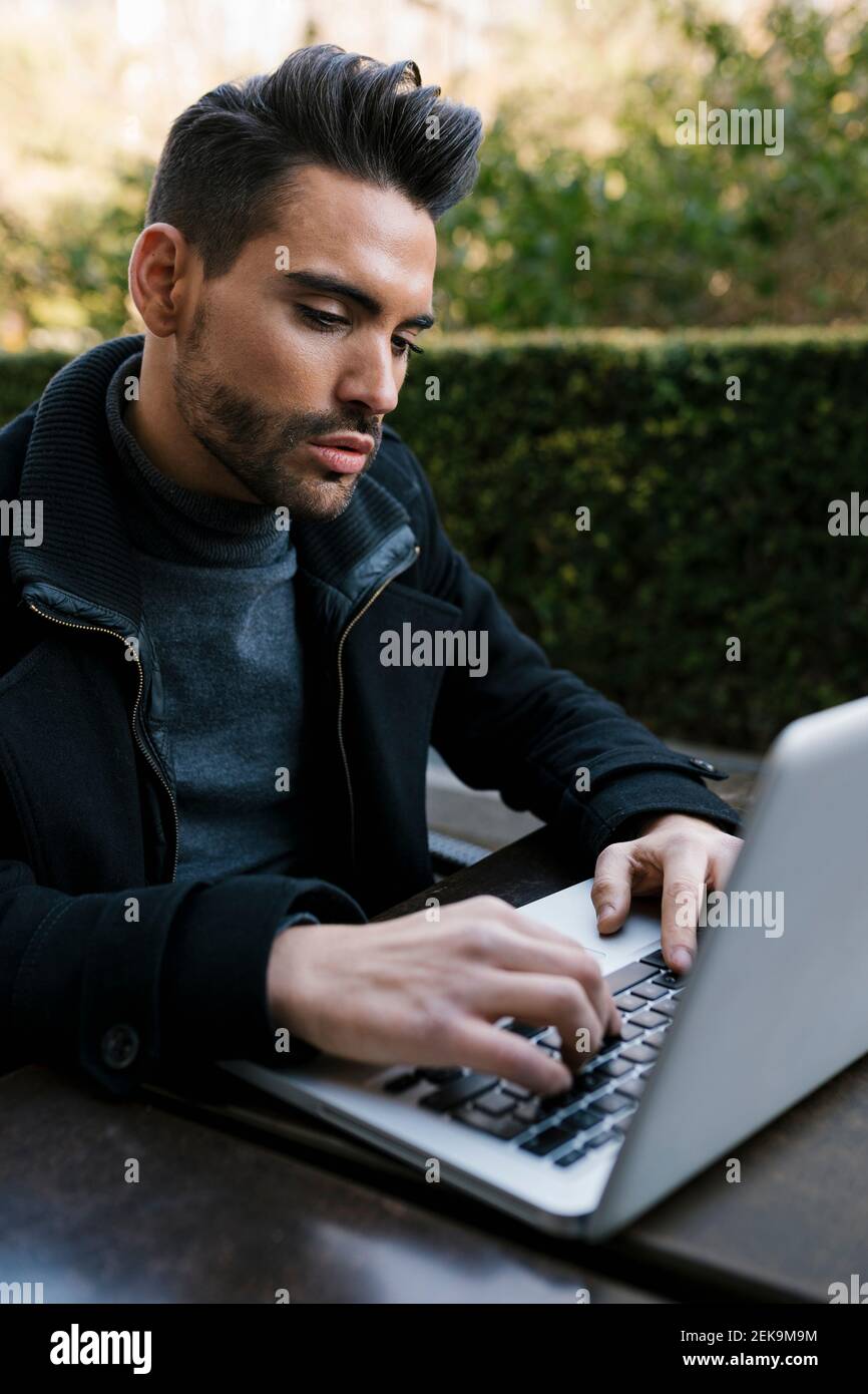 Handsome man using laptop while sitting at table Stock Photo
