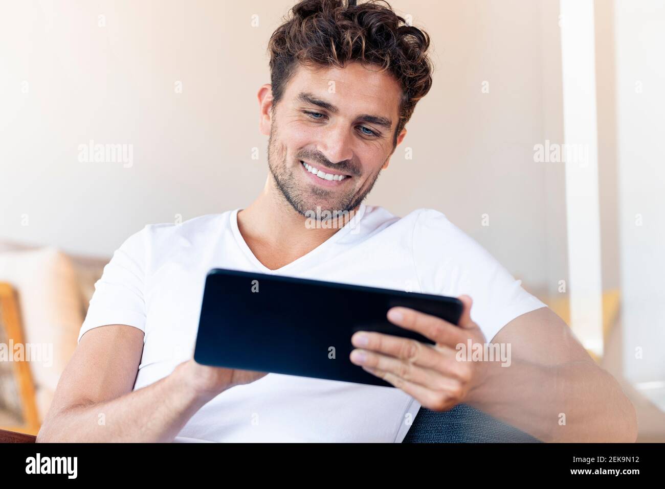 Mid adult man using digital tablet while sitting at home Stock Photo