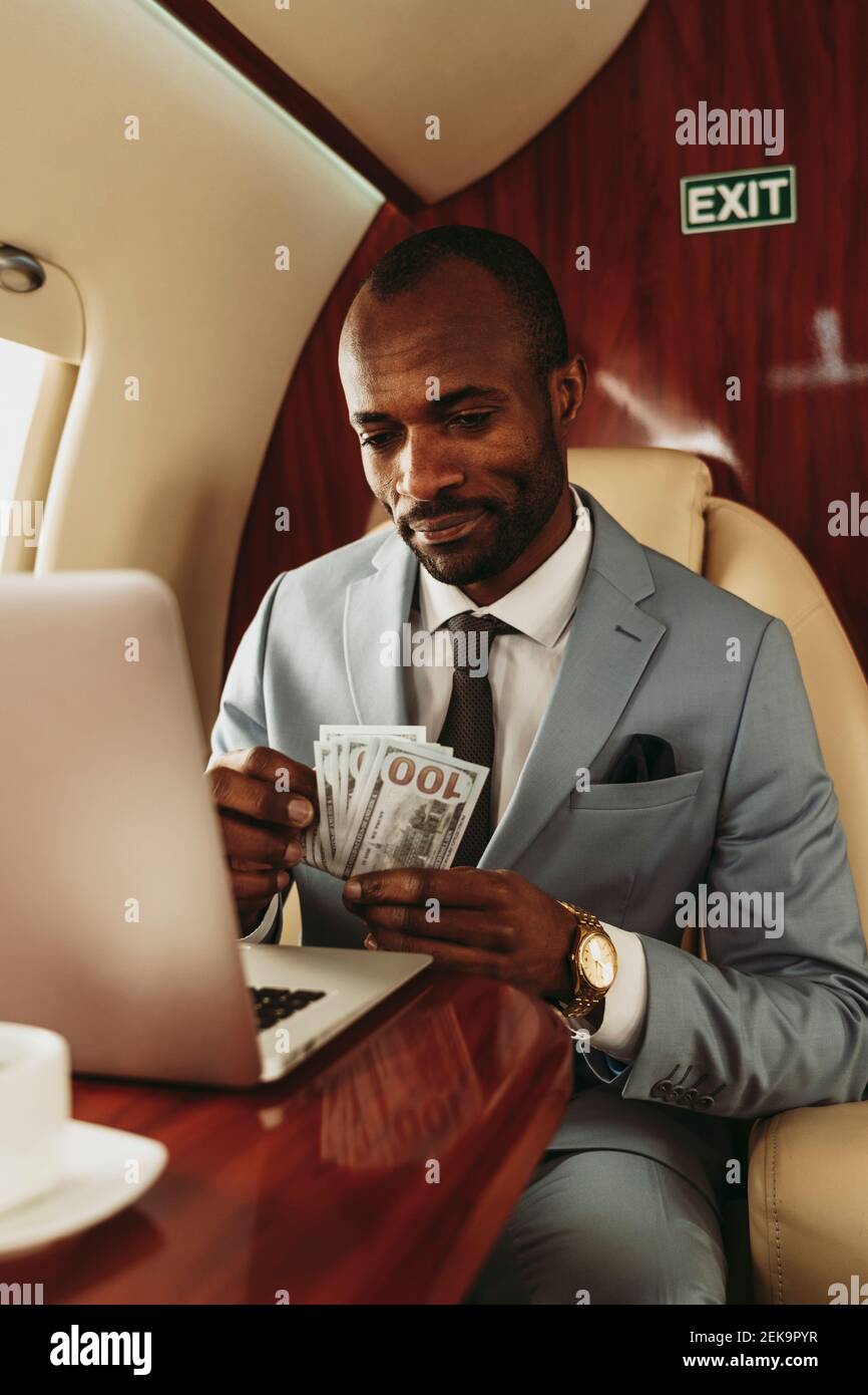 Businessman counting currency while traveling in private jet Stock