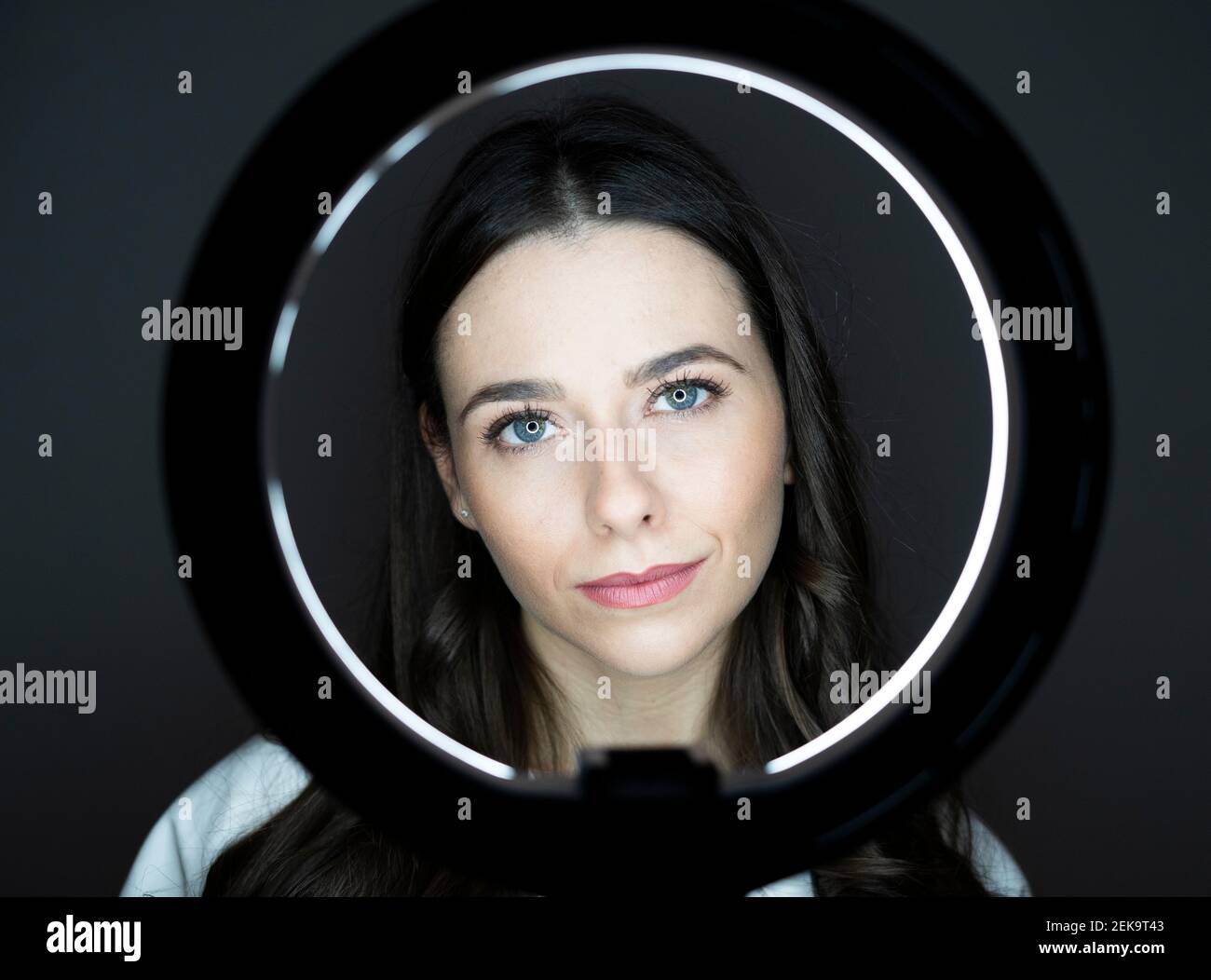 Beautiful woman looking through ring flash in studio Stock Photo