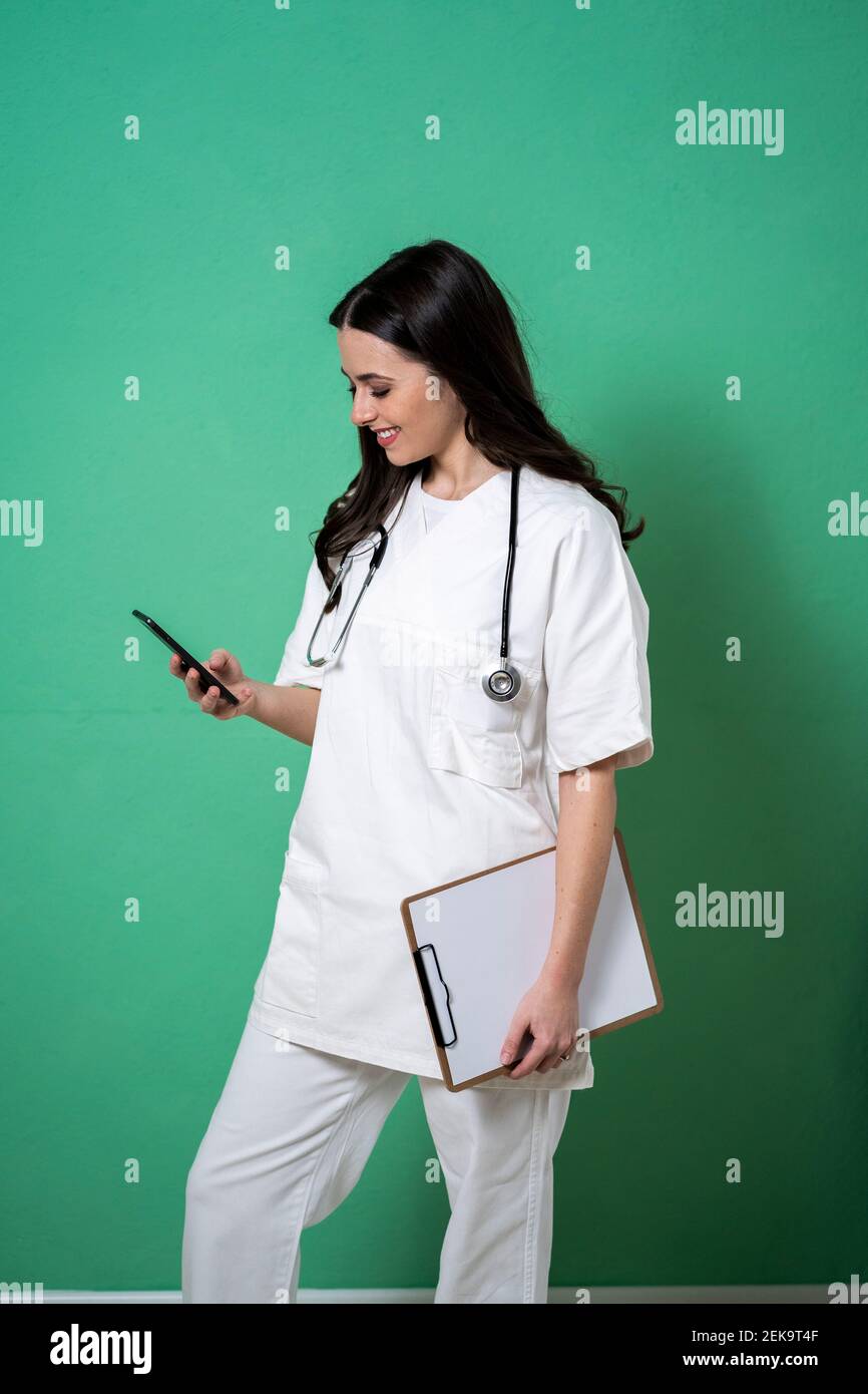 Smiling female doctor using smart phone in studio Stock Photo