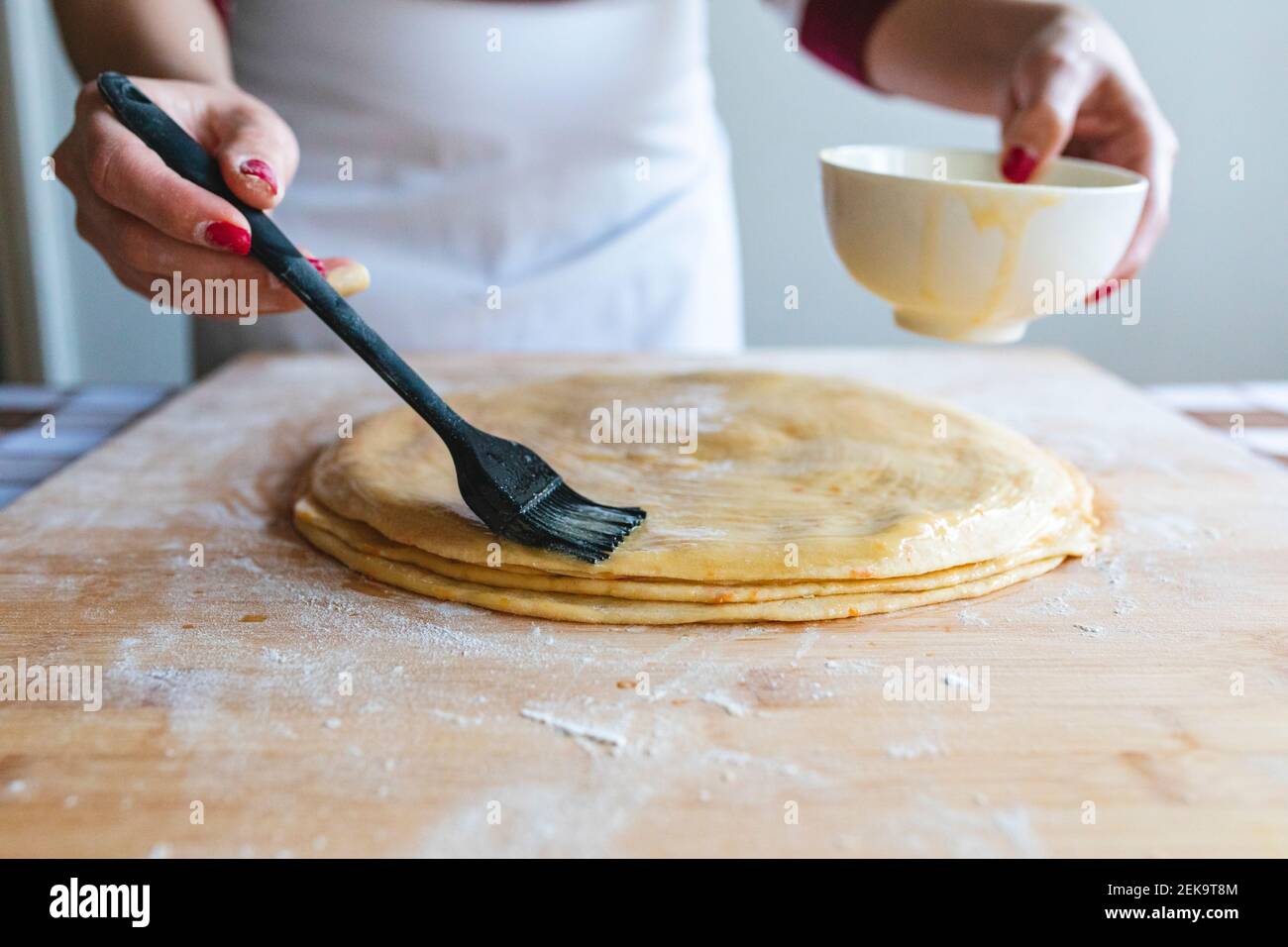 https://c8.alamy.com/comp/2EK9T8M/woman-applying-egg-on-dough-with-basting-brush-to-make-croissants-in-kitchen-2EK9T8M.jpg
