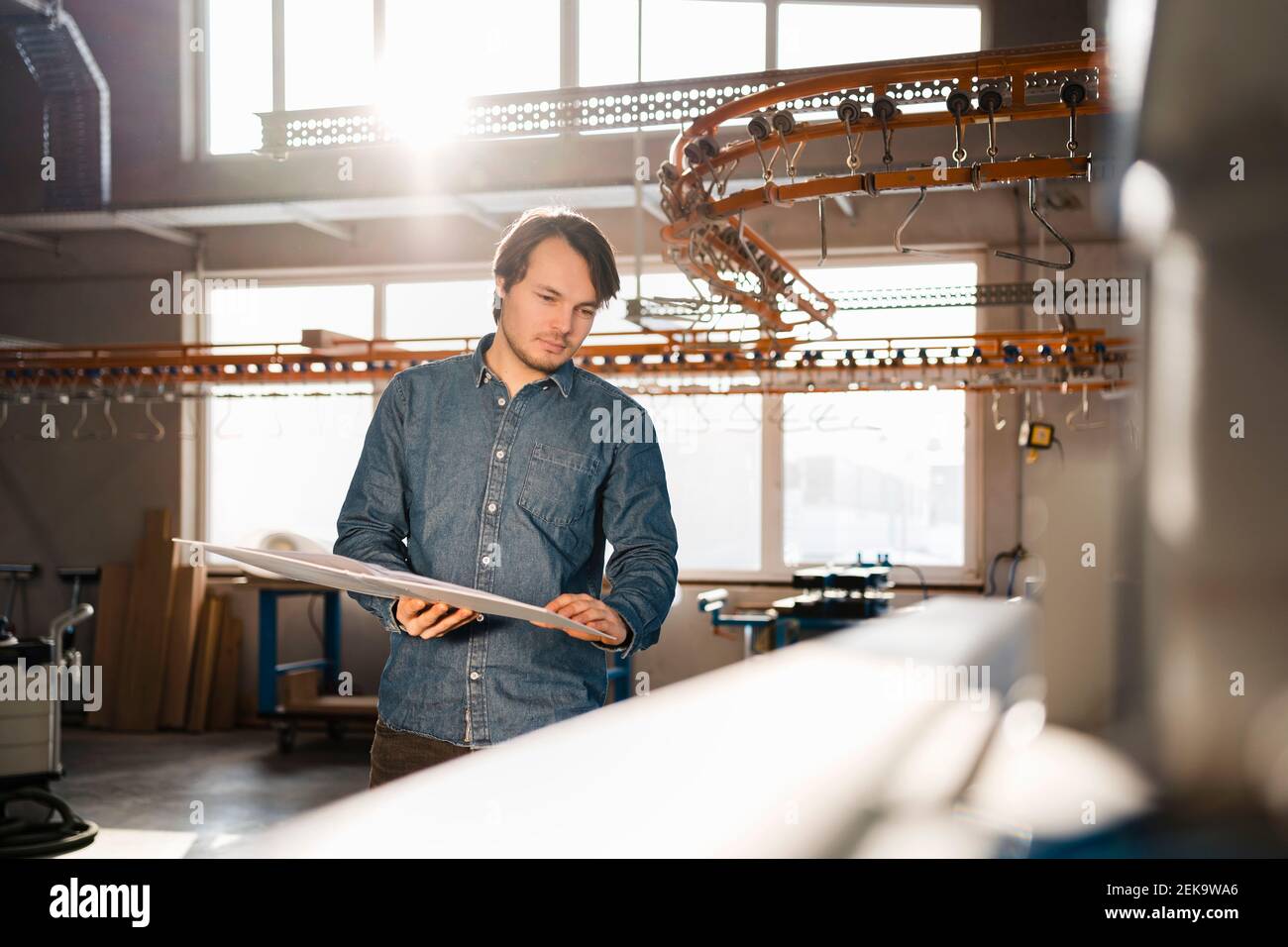 Young inspector holding file while standing by production line at industry Stock Photo