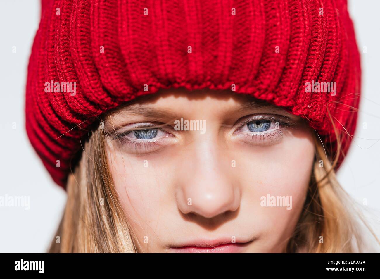 Contemplating girl in knit hat against wall Stock Photo