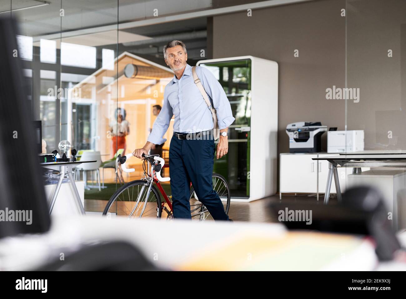 Mature businessman with bag and bicycle leaving after work from office Stock Photo