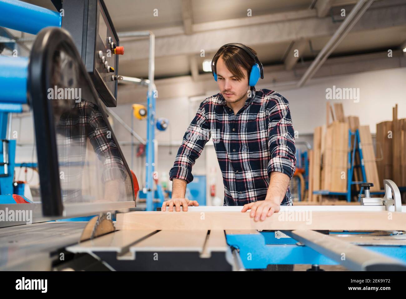 Industrial worker cutting wood in machine while standing at industry Stock Photo Alamy