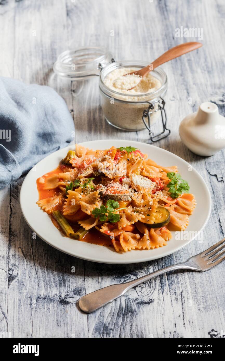 Two plates of bow tie pasta with vegetables and vegan Parmesan Stock Photo