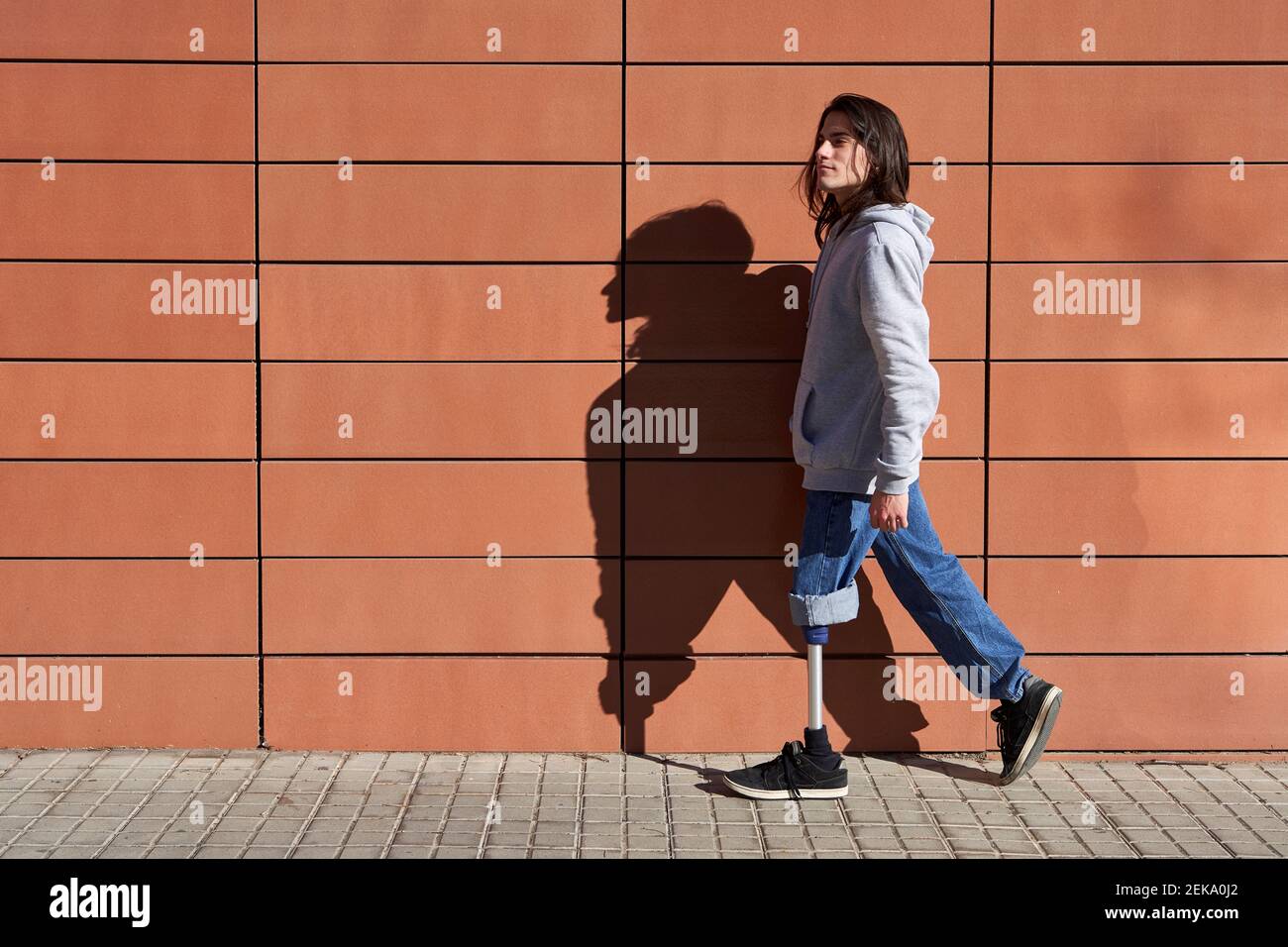 Disabled man with prosthetic leg walking by wall while looking away Stock Photo