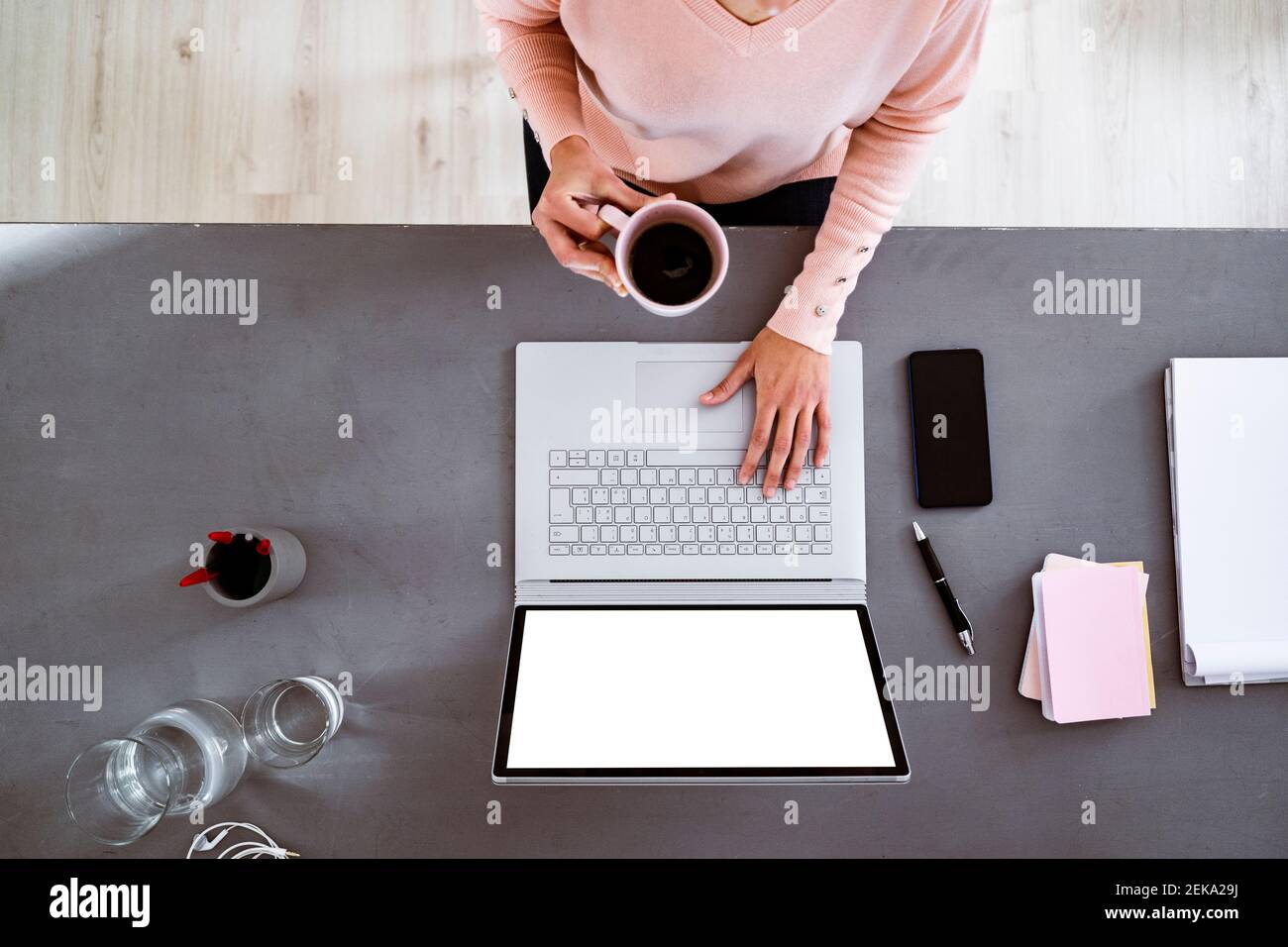 Young woman having coffee while using laptop while sitting at home Stock Photo