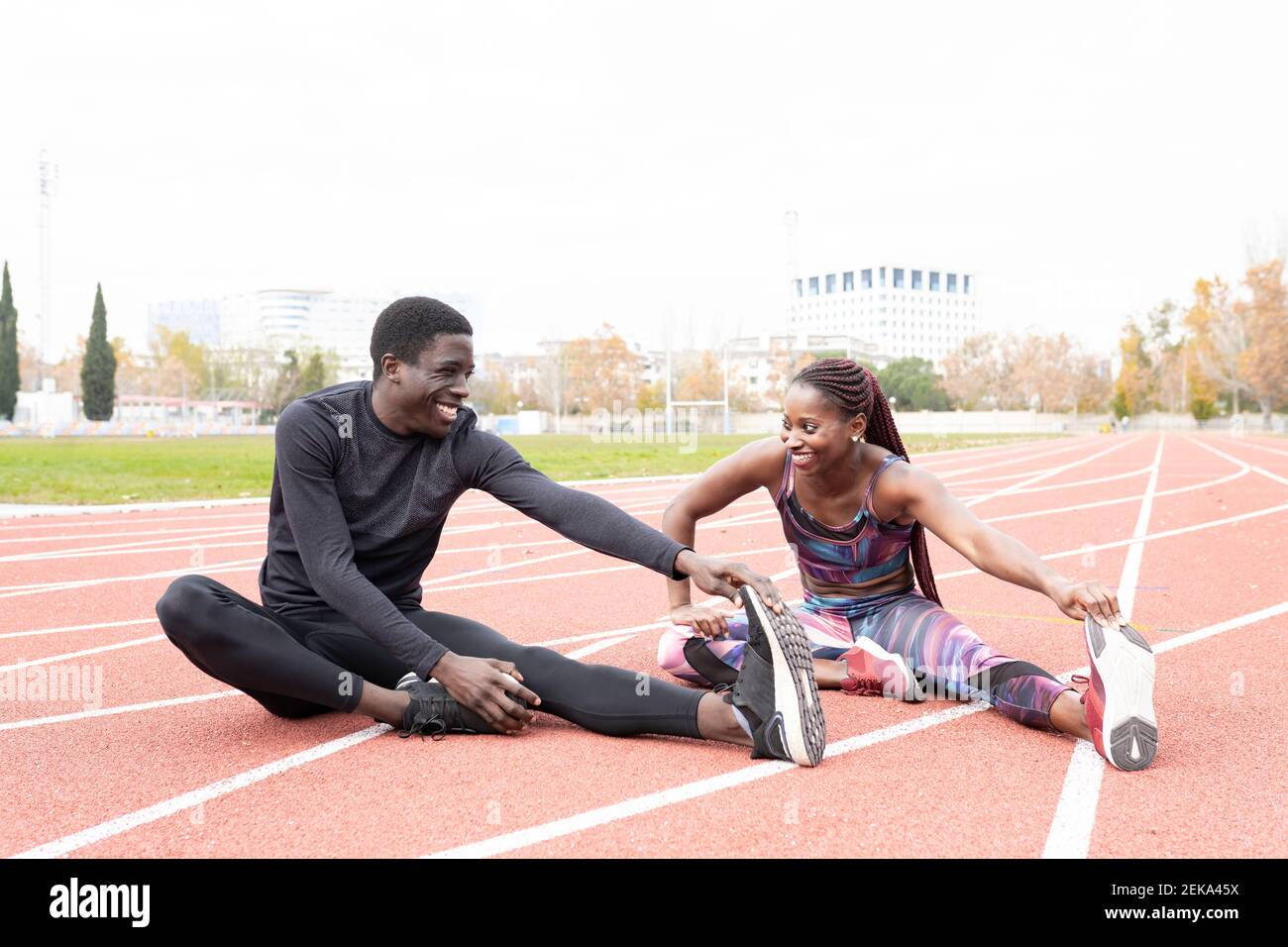 Happy male and female athlete doing warm up exercise while sitting on