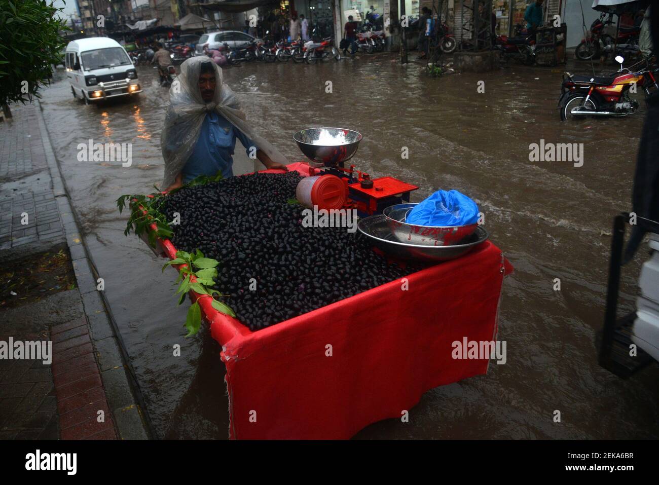 Pakistani commuters wade through a flooded street after heavy monsoon ...