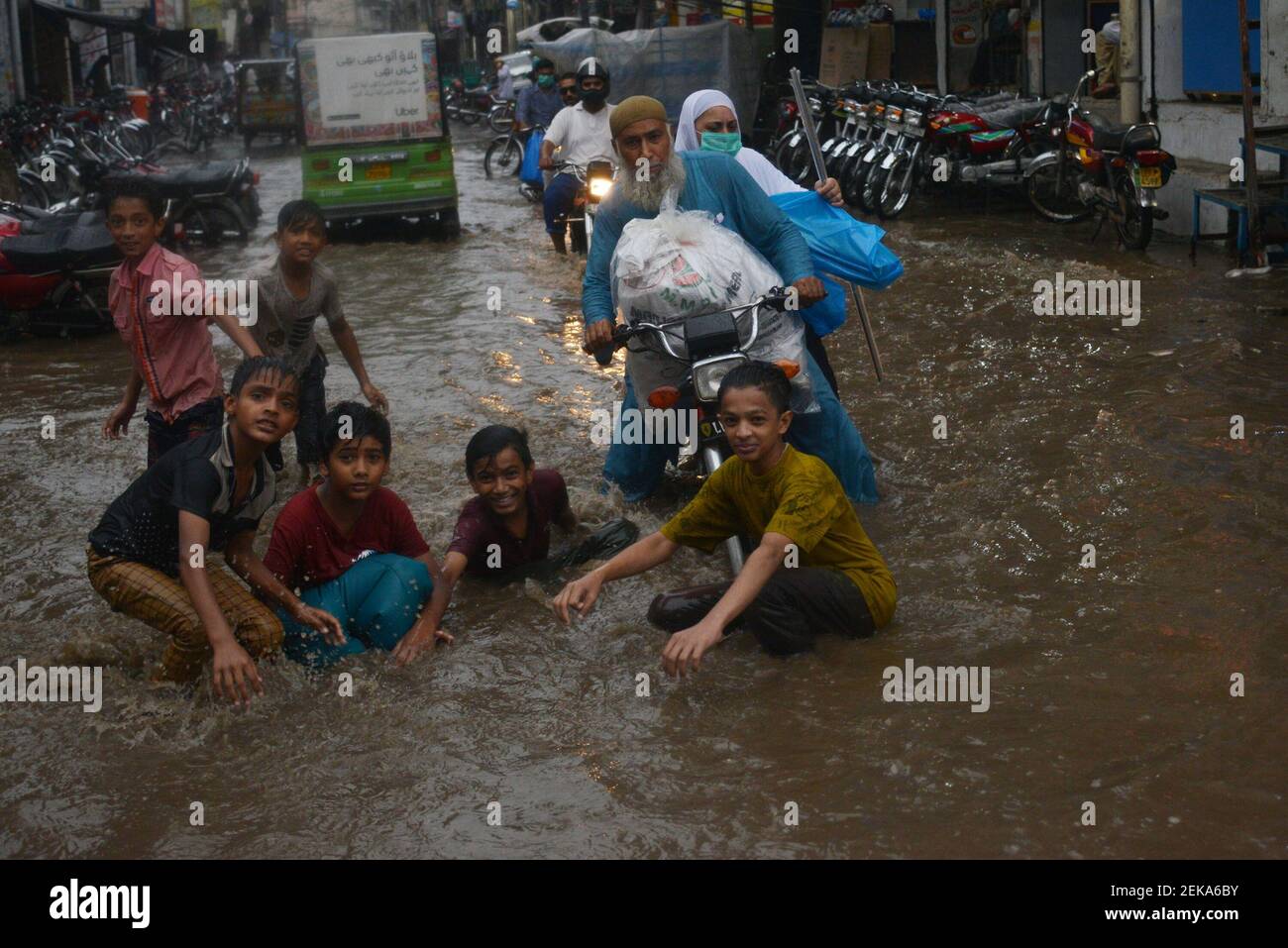 Pakistani commuters wade through a flooded street after heavy monsoon ...