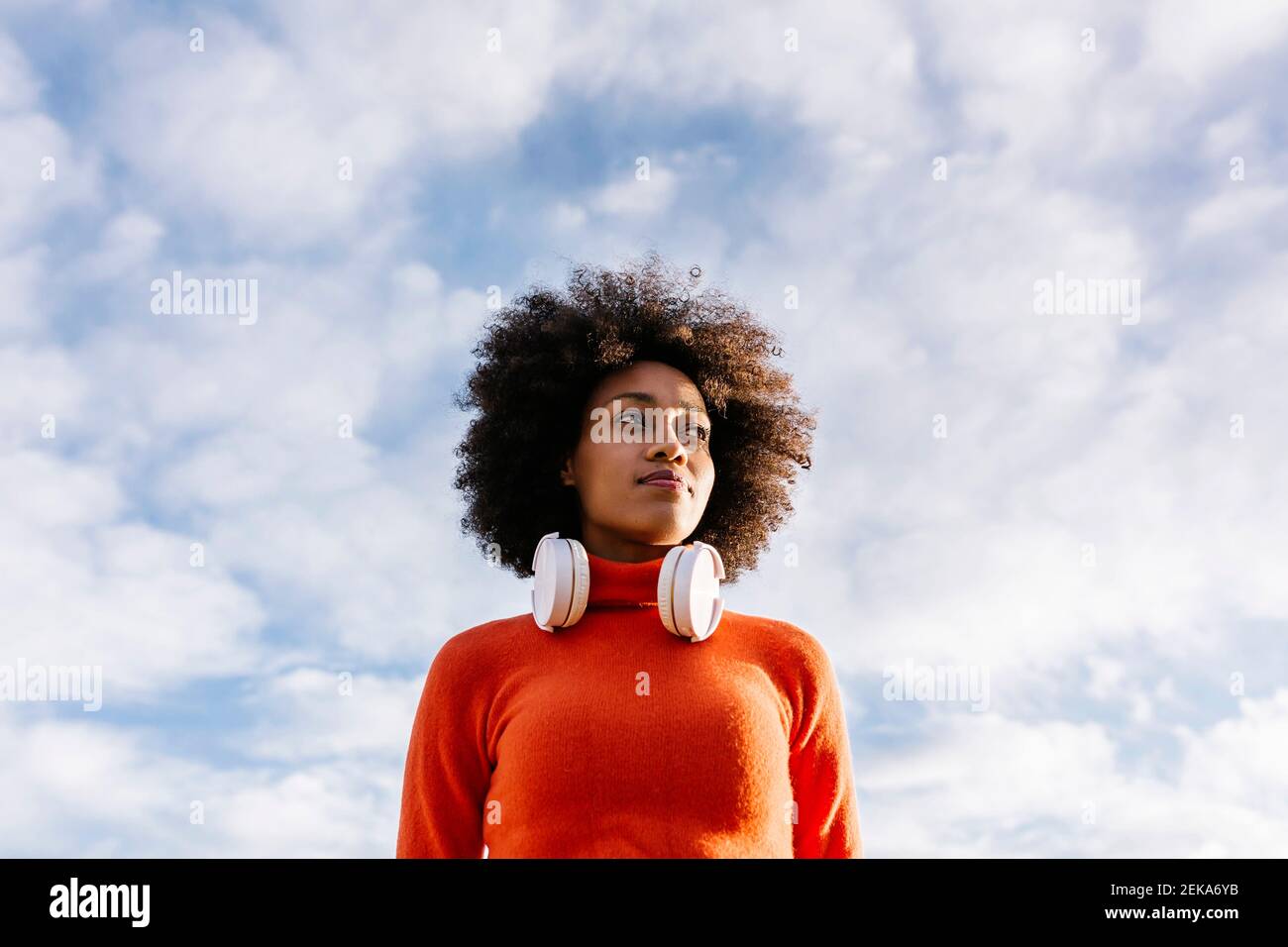 Contemplating Afro woman looking away against cloudy sky Stock Photo