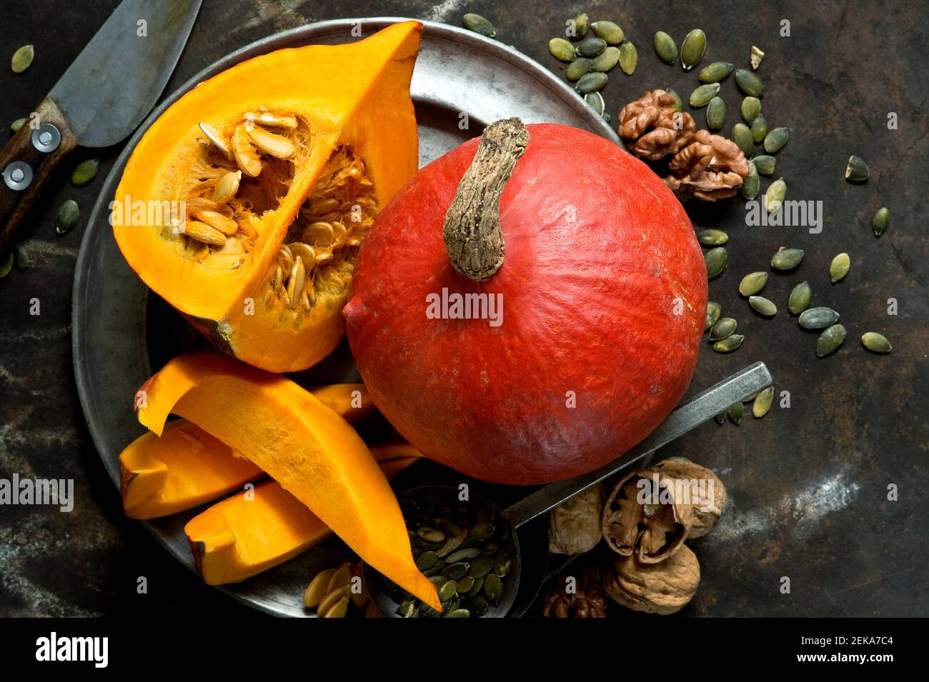 Walnuts, pumpkin seeds and red kuri squashes on rustic baking sheet Stock Photo